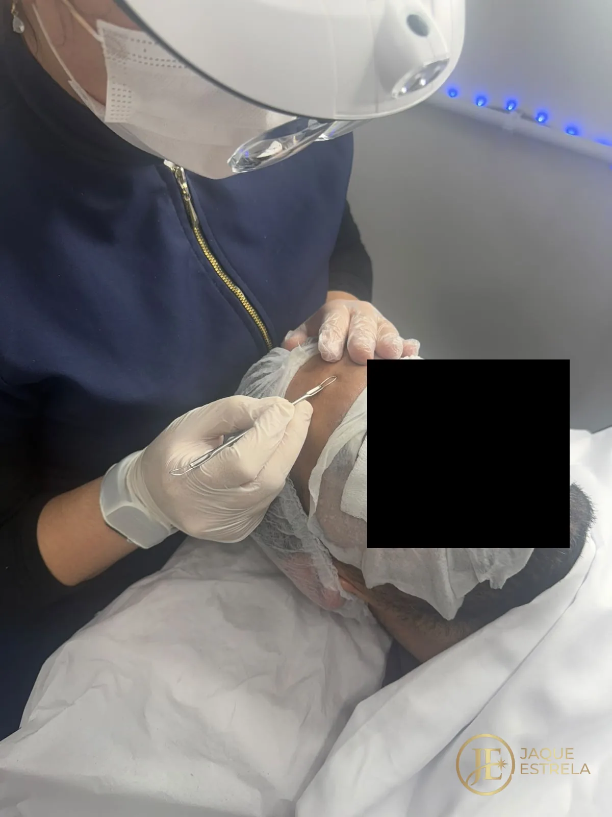 Jaque conduzindo limpeza de pele masculina com extração, sob luz de LED, no estúdio