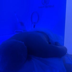 Cliente na maca durante a Massagem Revigorante, sob luz azul, no estúdio Jaque Estrela