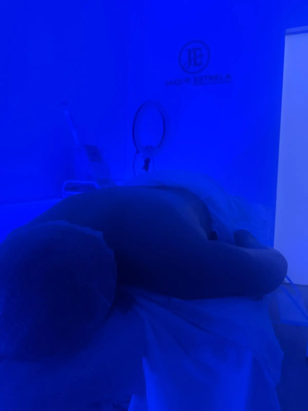 Cliente na maca durante a Massagem Revigorante, sob luz azul, no estúdio Jaque Estrela